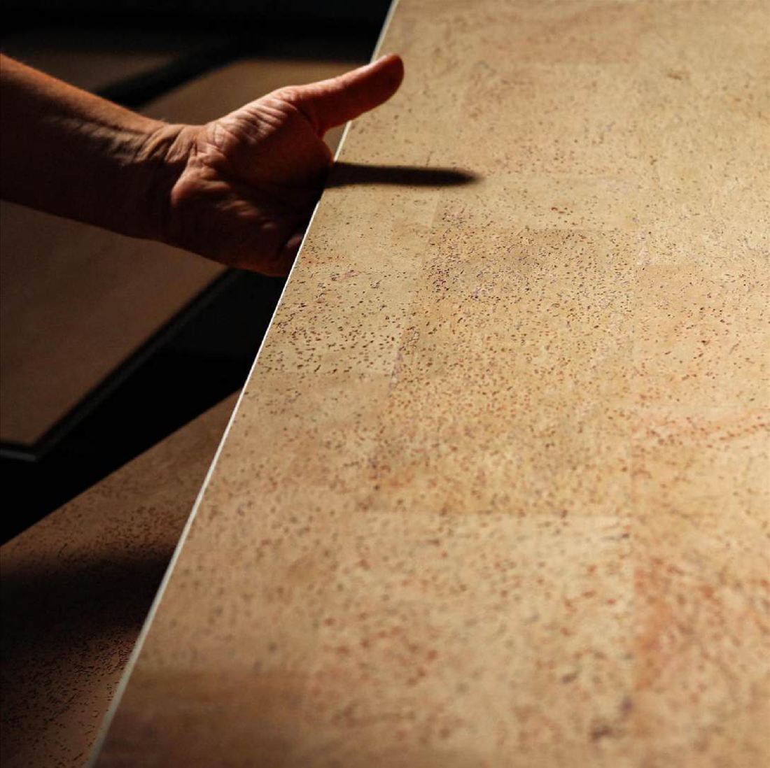 A hand running along the edge of a finished cork plank